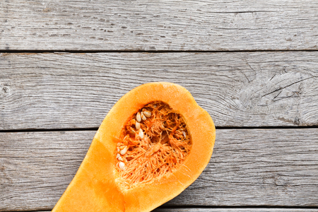Ripe big pumpkin cut on wooden background. Autumn vegetables harvest and cooking concept, top view with copy spaceの写真素材