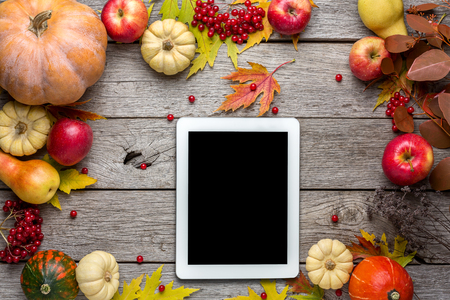 Fall background and mockup for seasonal sales. Tablet with empty screen for copy space in frame of pumpkins, yellow maple leaves and apples. Online holiday shopping concept, top viewの写真素材