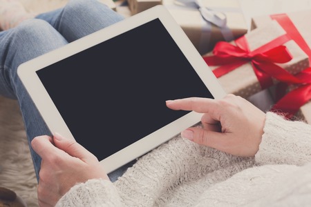 Christmas online shopping. Female buys presents to prepare to xmas eve at tablet, copy space on screen. Winter holidays salesの写真素材