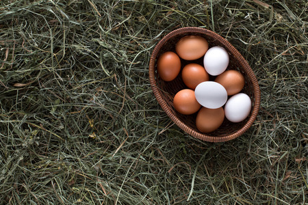 Poultry ecological farm background. Fresh brown and white eggs on hay in basket. Top view. Rural still life, natural organic healthy food concept. Copy spaceの写真素材