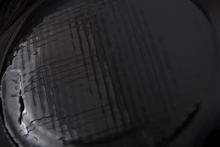 Abstract black textured background closeup. Wavy surface reflecting lightの写真素材