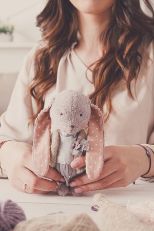 Process of making vintage toy, front view. Unrecognizable needlewoman sewing handmade rabbit at home workshopの写真素材