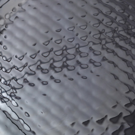 Abstract black textured background closeup. Wavy surface reflecting lightの写真素材