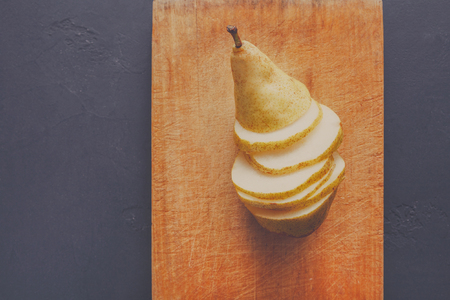 Sliced pear on wooden board background, top view, copy space, diet and vegetarian conceptの写真素材