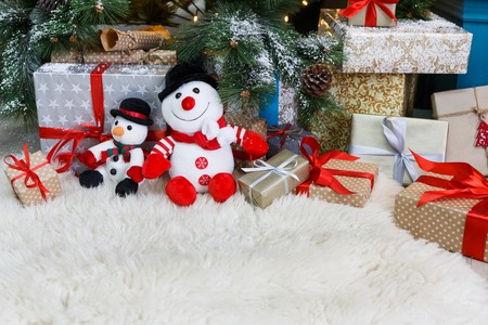 Cozy winter holidays background. Funny toy snowmen and presents waiting for christmas under decorated fir tree. Joyful and magical atmosphere of new year eve, copy spaceの写真素材