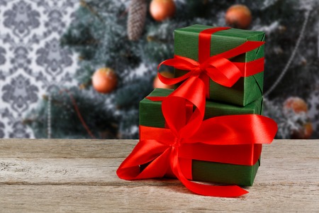 Christmas presents decorated with red ribbon on table, closeup, selective focus. Christmas tree background.の写真素材
