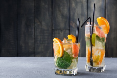 Summer citrus drinks at wooden background. Detox water with oranges, lemon and lime in glasses. Colorful backdrop with cold lemonade, copy space. Bar beverages or healthy eating dietary conceptの写真素材