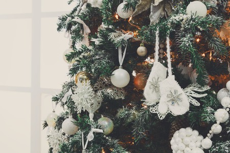 Winter holidays atmosphere background. Closeup of beautifully decorated fir tree with modern shiny baubles, beards, garland and small knitted mittens . Christmas and new year magic at home, copy spaceの写真素材