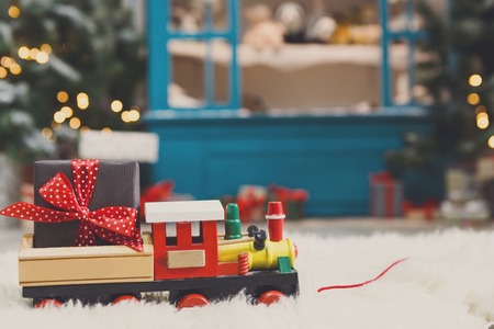 Wooden toy train with christmas gift on snowy decorated background. Selective focus, copy spaceの写真素材
