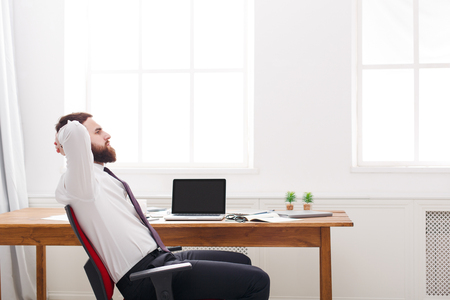 Side view of successful male employee. Young manager in white shirt with copy space. Relaxed man at workの写真素材