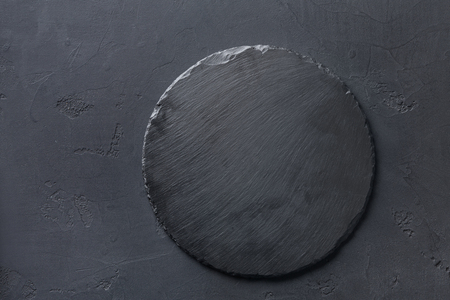 Empty rustic black slate stone plate on dark background, copy space, top viewの写真素材