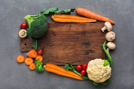Wooden desk with fresh vegetables border, cooking healthy food on gray background, copy space, top viewの写真素材