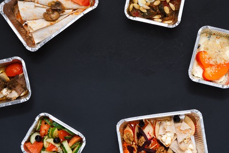Healthy restaurant food delivery background with copy space. Mockup for menu, foil containers with meals on blackの写真素材