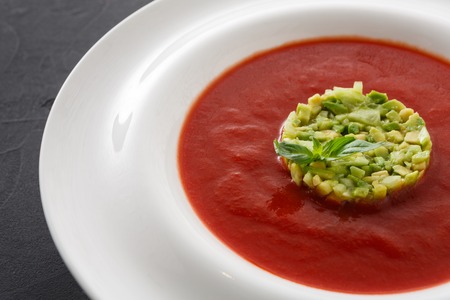 Delicious tasty cold tomato soup gazpacho with avocado close up. Portion of traditional Spanish red vegetable broth, restaurant servingの写真素材