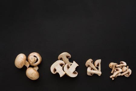 Stages of cutting mushrooms on black background. Chopping fresh vegetables, cooking healthy food.の写真素材