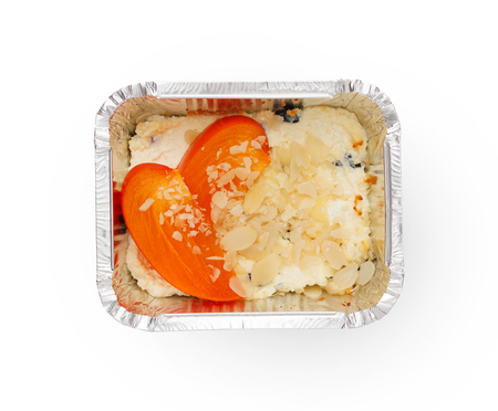 Healthy lunch in foil container. Healthy food take away and delivery. Cottage cheese with persimmon and almonds chips in box on white background, closeup, isolatedの写真素材