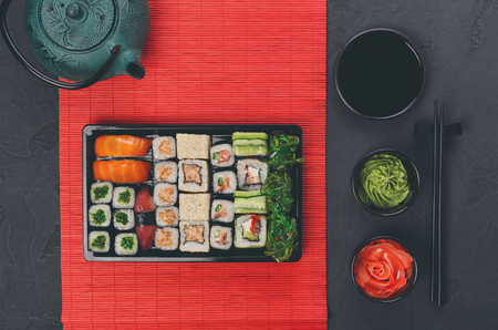 Colorful sushi and rolls platter in japanese restaurant, with teapot and chopsticks top view.の写真素材