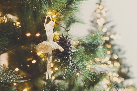 Christmas tree holiday background. Xmas magic and beauty. Fluffy pine tree branches with pinecones with snow and decorated with elegant toy ballerina and garland, closeup, copy space, selective focusの写真素材