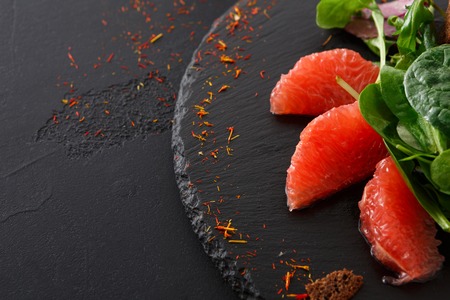 Gourmet seafood snack on black plate close up. Appetizing meal with red salmon, caviar and crispy toasts, restaurant servingの写真素材