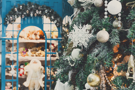 Decorated christmas trees background. Fluffy green pines in shiny garland and lots of toys for childen. Xmas and new year eve atmosphere, closeup, copy spaceの写真素材