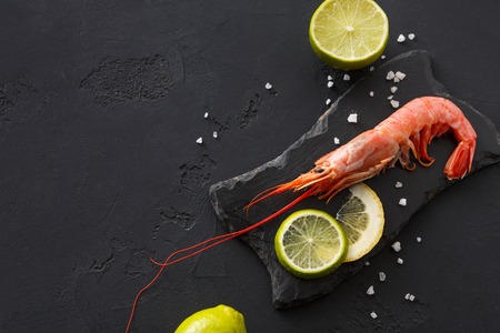 Boiled shrimp with salt and lemon on black background, copy space. Top view on appetizing seafood snack, restaurant serving.の写真素材