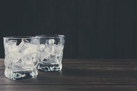 Glasses with ice cubes on dark background. Cold summer cocktail preparing, refreshment conceptの写真素材