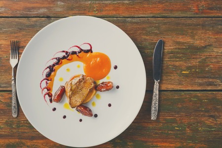Roasted goose liver with date and apple, fruit and berry sauce painting and cutlery top view. Creative french cuisine, delicatessen restaurant mealの写真素材