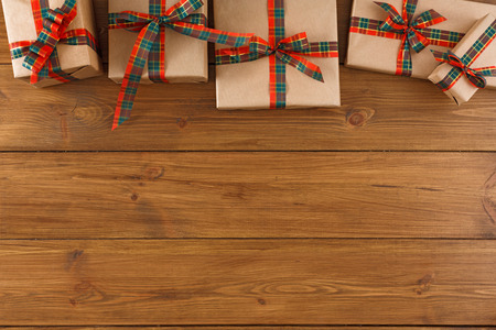 Gift boxes border, top view with copy space on wood table background. Frame of colored packages with red, green ribbons for christmas, valentine day or birthdayの写真素材