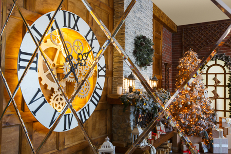 Beautiful holdiay living room with lots of presents under decorated christmas tree, fireplace and huge clock reflecting in mirror. Winter holiday design and decorations backgroundの写真素材