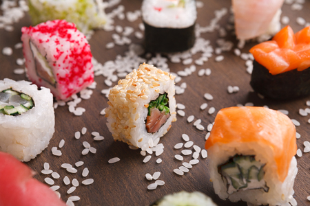 Japanese food restaurant delivery - sushi maki california roll big party platter set with sesame on wooden rustic background, closeupの写真素材