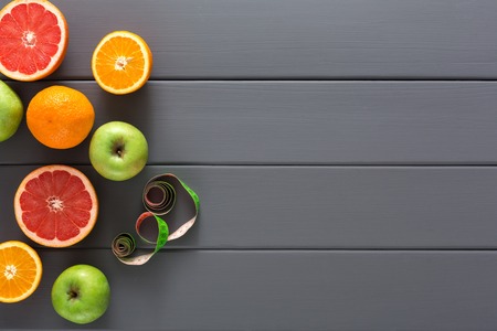 Slomming background. Grapefruitt, orange and apple with measuring tape on grey wood with copy space. Diet, healthy eating conceptの写真素材
