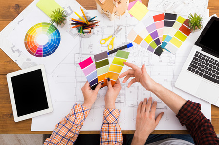 Interior designers teamwork with pantone swatch and house building plans on office desk, architects...