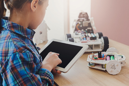 Stem education. Creating robotics project, mockup. Concentrated girl drawing plan of innovation robot model in blank digital tablet, diy conceptの写真素材