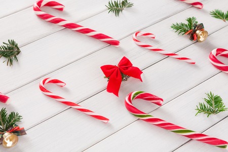 Sweet christmas background and pattern. Traditional candy canes and small bells on white wood. Xmas and other winter holidays concept with copy spaceの写真素材