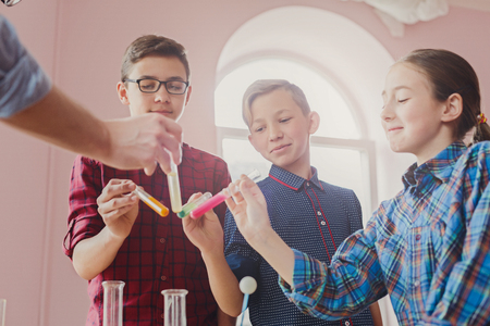 Stem education. Pupils with teacher doing biochemistry research in chemistry class, using laboratory tubes with colorful liquidsの写真素材