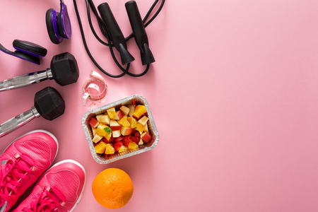 Fitness background, sport equipment, copy space. Jumping rope, bottle, sneakers, mat and measuring tape on pink backgroundの写真素材