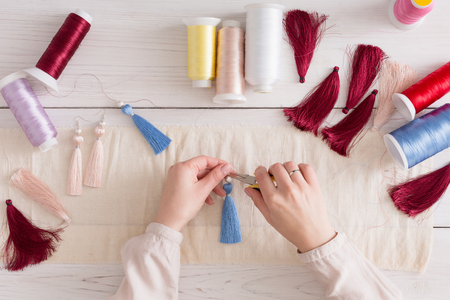 Handmade earrings making, home workshop. Woman artisan create tassel jewelry, top view. Art, hobby, handicraft conceptの写真素材