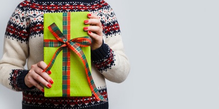 Unrecognizable woman holding christmas gift. Cropped image of girl in sweater with present box in...