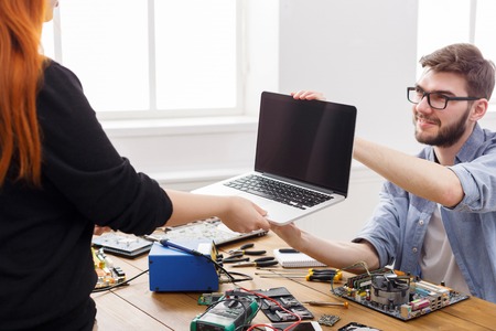Engineer taking broken laptop from client. Acceptance of damaged electronic device in repair service...
