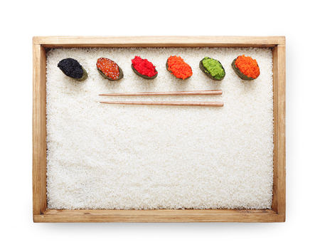 Top view on sushi gunkan with colored caviar in wooden frame with chopsticks on white rice background and texture copy space,isolatedの写真素材
