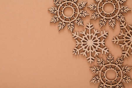 Wooden snowflakes christmas background. Craft decorations border for copy space on beige surface. Handmade ornaments for new year and other winter holidays, top viewの写真素材