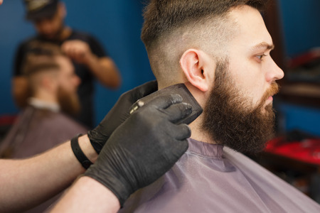 Barber styling beard with trimmer at barbershop, closeup of clients head. Barbershop for menの写真素材