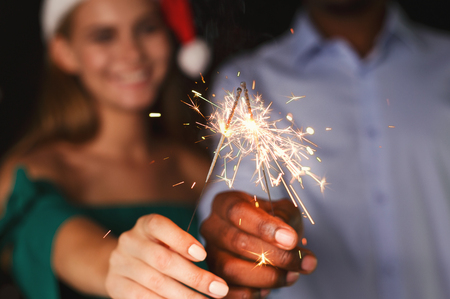 Holiday background with sparklers. Young friends holding bengal lights, closeup, selective focus. Birthday or winter holidays celebration, greeting card mockupの写真素材