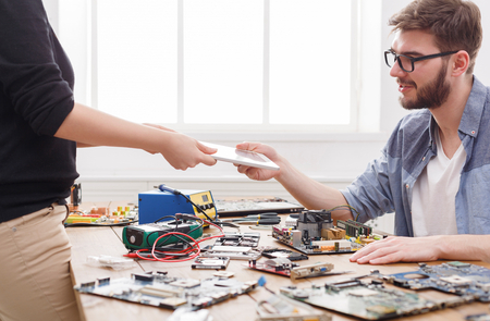 Engineer taking broken digital tablet from client. Acceptance of damaged electronic device in repair...