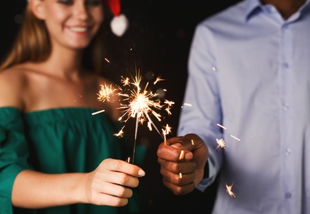 Holiday background with sparklers. Young friends holding bengal lights, closeup, selective focus. Birthday or winter holidays celebration, greeting card mockupの写真素材