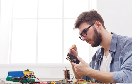 Engineer holding winchester disk in hands. Repairman fixing broken computer hard disk in electronic repair shop, copy spaceの写真素材