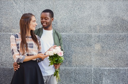 Man giving flowers for his beautiful girlfriend, having anniversary date, copy space