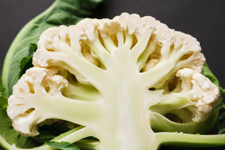 Stages of cutting cauliflower on black background. Chopping fresh vegetables, cooking healthy food.の写真素材