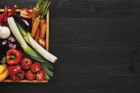 Heap of fresh organic vegetables and greens in square case at black wood background. Healthy natural food with copy space. Tomato, pepper, pumpkin and other cooking ingredients top viewの写真素材