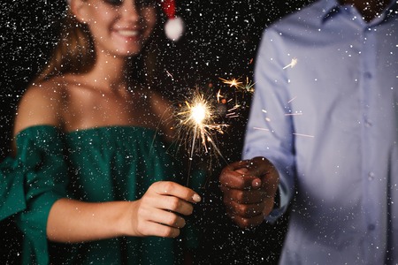 Holiday background with sparklers. Cropped shot of young friends holding bengal lights, closeup, selective focus. Birthday or winter holidays celebration, greeting card mockupの写真素材